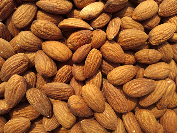 Nahaufnahme ungeschälter brauner Mandeln – natürliche Rohstoffe für pflegendes Süßmandelöl (Prunus Amygdalus Dulcis Oil)
