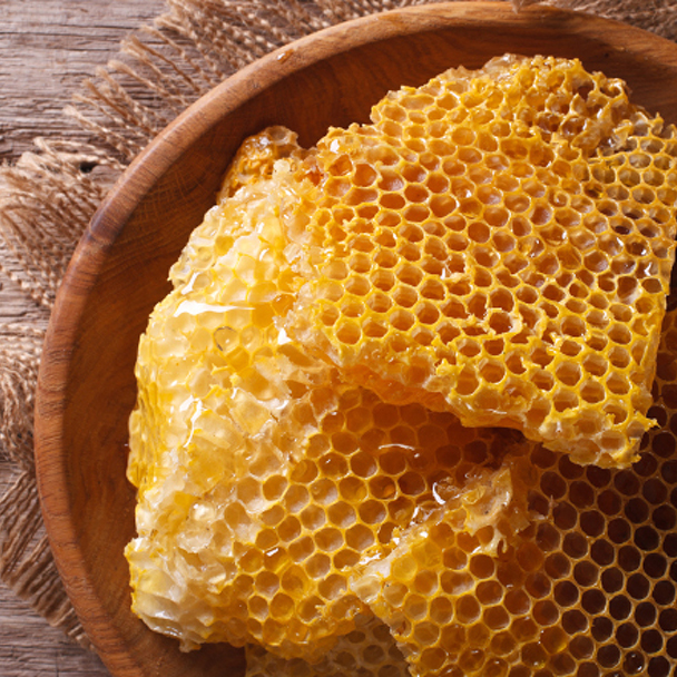 Frische goldgelbe Honigwabe auf einem Holzteller – natürliche Quelle von Bienenwachs (Cera Alba).