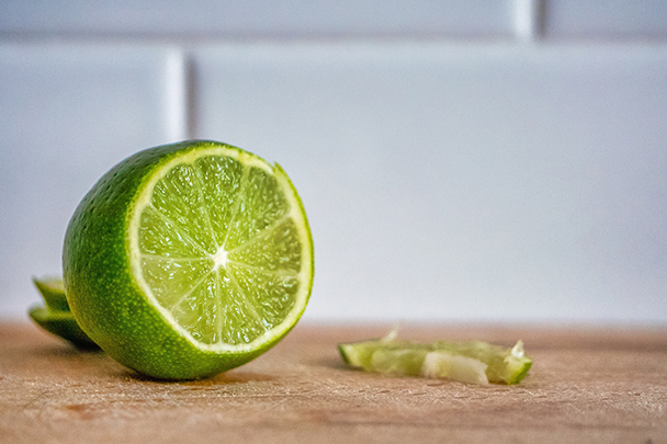 Halbierte grüne Limette mit Schale auf einem Holzbrett – Quelle des Citrus Aurantifolia (Lime) Peel Extract.