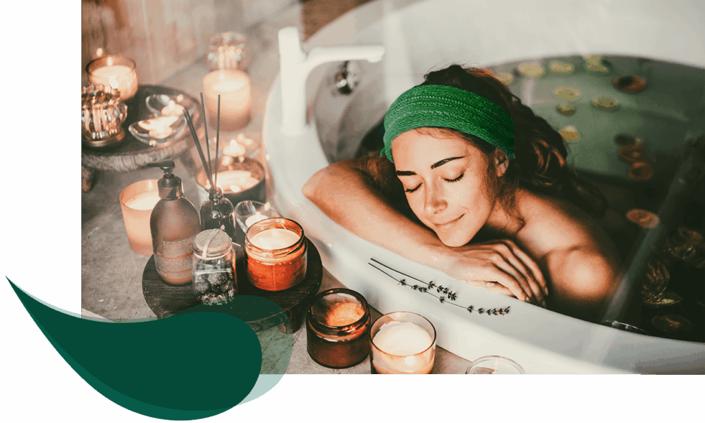 Frau entspannt in einer Badewanne mit geschlossenen Augen, umgeben von Kerzen, Badeprodukten und Lavendel – Atmosphäre purer Erholung und Wohlbefinden.