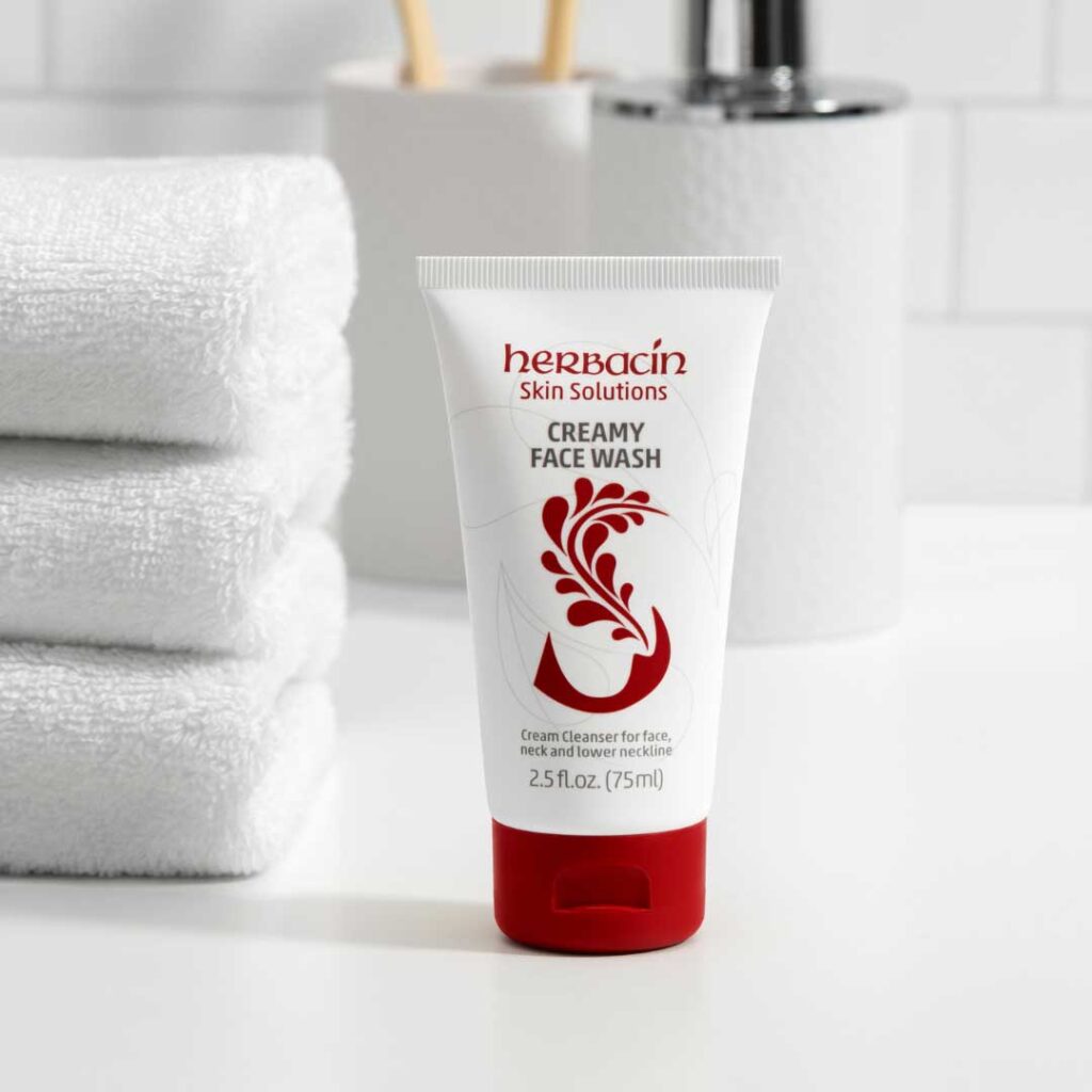 Herbacin Skin Solutions Creamy Face Wash auf weißem Badezimmerhintergrund mit gestapelten Handtüchern – sanfte Reinigung für Gesicht und Hals.