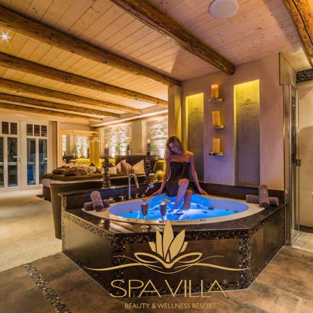 SPA-Villa-Wingerode Frau sitzt am beleuchteten Whirlpool im stilvollen Ambiente der Spa Villa in Wingerode – luxuriöses Wellness-Resort mit Kamin und Holzdecke.