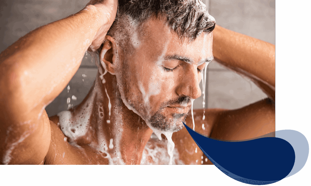 Mann unter der Dusche, eingeseift mit Shampoo, entspanntes Gesicht, Wasser rinnt über Haare und Körper.